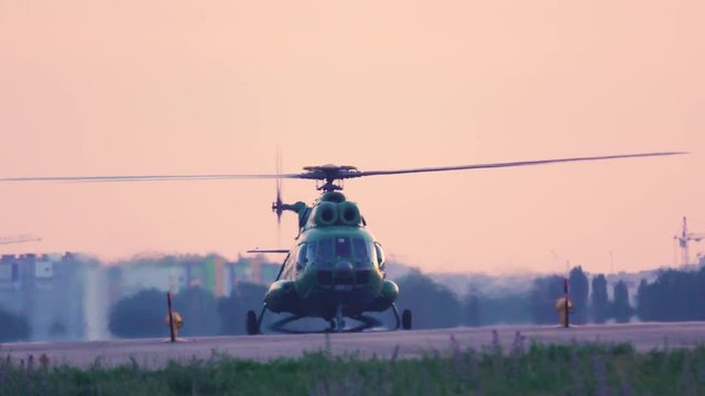 Military helicopter stands on the airfield before take off at sunset 