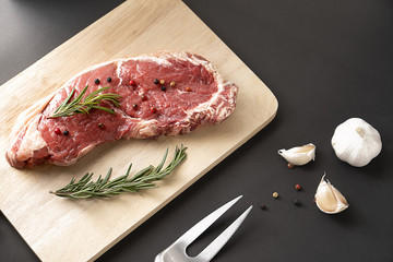 Fresh raw  beef steaks with pepper rosemary on wood board