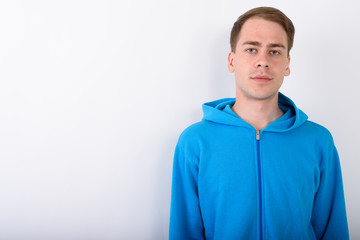 Young handsome man wearing blue hoodie against white background