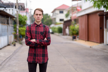 Young handsome man wearing red checkered shirt in the streets ou