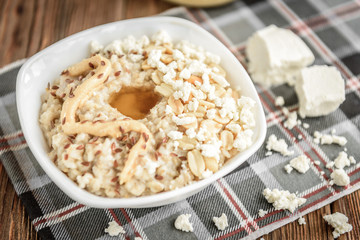 Homemade oatmeal with honey, peanut butter, peanut, flax seeds and cottage cheese on wooden background. Healthy breakfast.