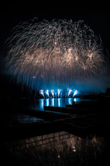 Beautiful colorful fireworks display on celebration night Celebration fireworks over the river with cityscape soft focus background at night scene