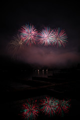 Beautiful colorful fireworks display on celebration night Celebration fireworks over the river with cityscape soft focus background at night scene
