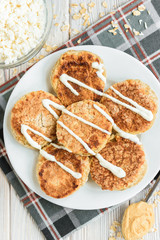 Oat cottage cheese pancakes with sour cream and peanut butter on white wooden background. Healthy breakfast, snack or diner.
