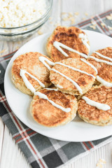 Oat cottage cheese pancakes with sour cream and peanut butter on white wooden background. Healthy breakfast, snack or diner.