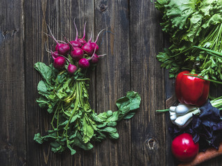 overhead bunch of radish on a wooden surface with mix of fresh vegetables and herbs