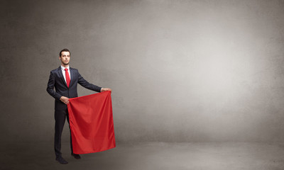 Businessman standing with red toreador cloth in his hand in an empty room
