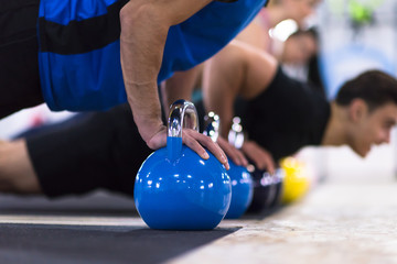 young athletes doing pushups with kettlebells - Powered by Adobe