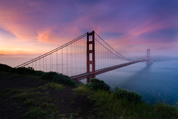 Fototapeta na wymiar Golden Gate bridge during sunrise with the city view background