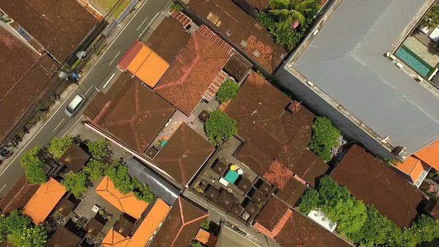 Aerial top view of houses with orange tile roofs and asphalt road in Seminyk, Bali, Indonesia on sunny summer day