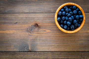 Fresh recently picked blueberries in bowl on dark wooden background top view copy space closeup