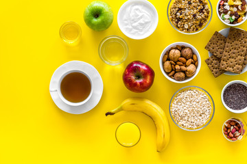Fototapeta na wymiar Ideas of healthy hearty breakfast for sportsmen. Fruits, oatmeal, yogurt, nuts, crispbreads, chia on yellow background top view copy space