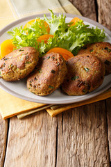 Tuna patties with herbs and fresh vegetable salad close-up on a plate. vertical