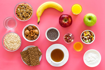 Layout of products for healthy and hearty breakfast. Fruits, oatmeal, yogurt, nuts, crispbreads, chia on pink background top view