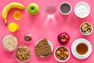 Layout of products for healthy and hearty breakfast. Fruits, oatmeal, yogurt, nuts, crispbreads, chia on pink background top view copy space