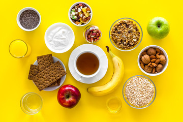 Obraz na płótnie Canvas Layout of products for healthy and hearty breakfast. Fruits, oatmeal, yogurt, nuts, crispbreads, chia on yellow background top view copy space