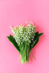 May flowers. Bouqet of lily of the valley flowers on pastel pink background top view copy space