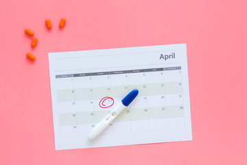 Planning pregnancy. Positive pregnancy test near calendar page and pills on pink background top view copy space