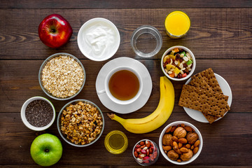 Obraz na płótnie Canvas Set of products for healthy vegetarian breakfast. Fruits, oatmeal, yogurt, nuts, crispbreads, chia on dark wooden background top view