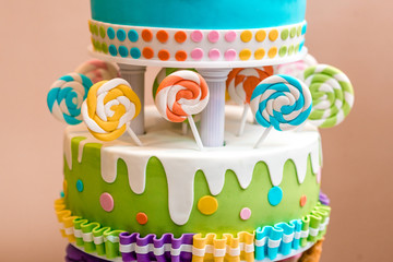Beautiful multi-colored children's cake from several layers decorated with sweets.