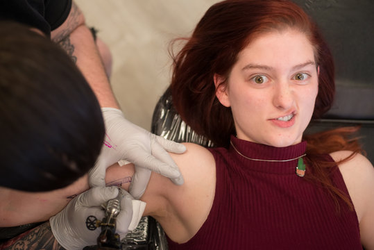 Grimacing Girl Getting Tattoo