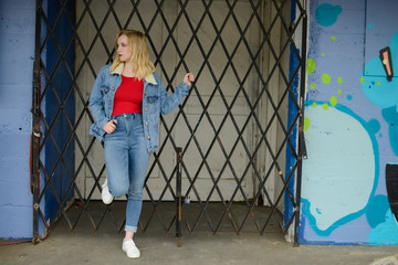 Beautiful Blonde Teen Leaning Against Urban Gate