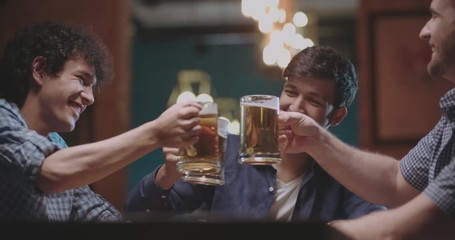 three young friends drinking beer in bar or pub 4k dollyshot - Powered by Adobe