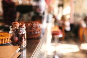 The counter in the cafe is a blurred background. Nuts in the bank in the foreground, interior of the cafe in the background