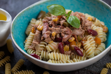 Bowl of fusilli pasta with tuna fillet, red beans and corn seeds, selective focus, closeup
