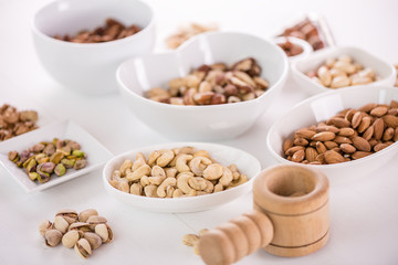 variety, mixture of different nuts on white background in white bowls 