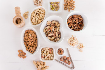 variety, mixture of different nuts on white background in white bowls 
