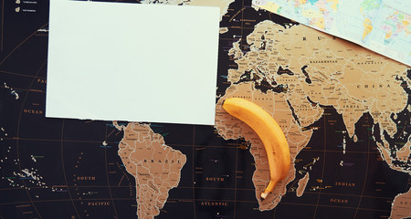 Banana on the black map of the world. The concept of tropical fruits