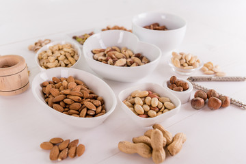variety, mixture of different nuts on white background in white bowls 