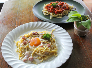 Spaghetti Carbonara with egg yolk and Spaghetti italian pasta with tomato sauce on wooden table