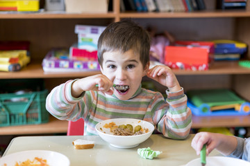 A boy at the age of 5 years eating gruel in the kindergarten.