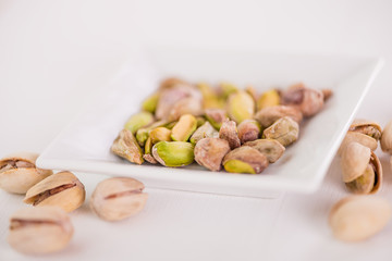 pistachio nuts in white dish on white background