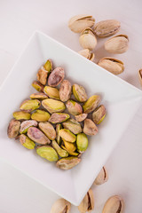 pistachio nuts in white dish on white background
