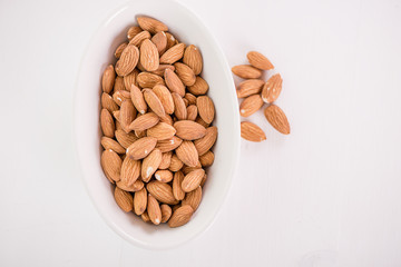 heap of almonds in white dish on white background 