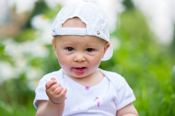 Sweet little child, baby boy, eating cherries in garden, enjoying tasty fruit