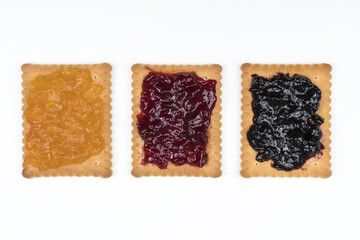 Some dry biscuits with jam on a white surface