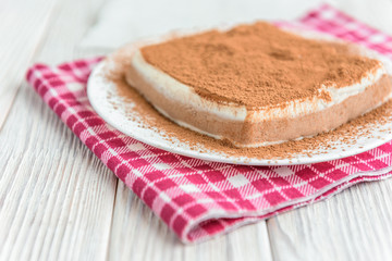 Homemade layered cottage cheese souffle dessert with cocoa on white wooden table