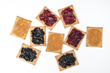 Some dry biscuits with jam on a white surface