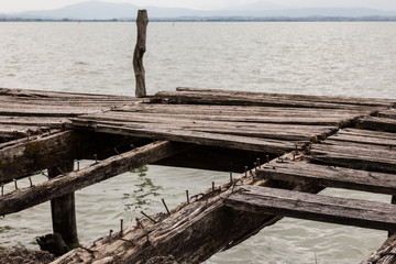 Details of an old, broken pier on a lake, with nails and worn and missing wood boards