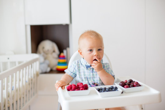 Adorable little baby boy, eating fresh fruits at home