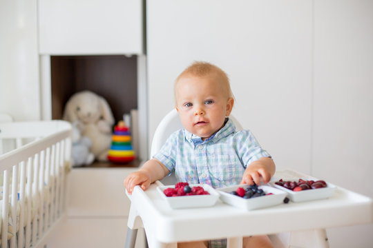 Adorable little baby boy, eating fresh fruits at home