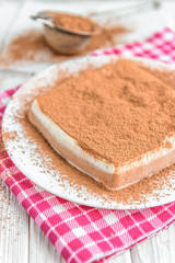 Homemade layered cottage cheese souffle dessert with cocoa on white wooden table