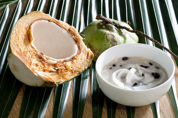 Sago (thai product) and black beans in coconut cream with young coconut, in white bowl on coconut...
