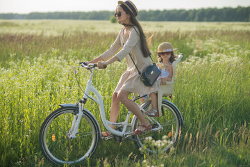 Mother and daughter have bike ride on nature. Summertime activity