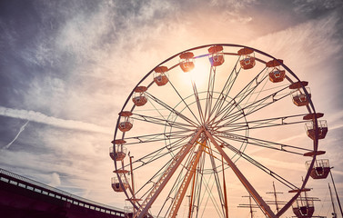Vintage toned picture of a Ferris wheel at sunrise.
