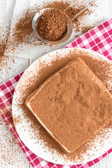 Homemade layered cottage cheese souffle dessert with cocoa on white wooden table